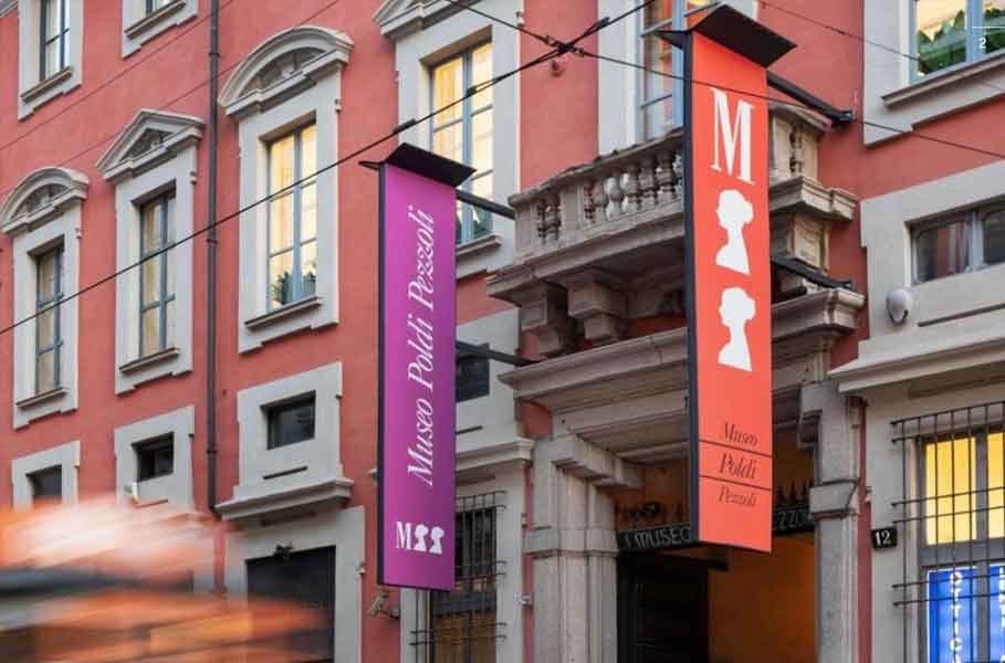 Un'insegna viola e un'altra arancione indicano l'entrata del Museo Poldi Pezzoli in una strada urbana, fiancheggiata da edifici storici.