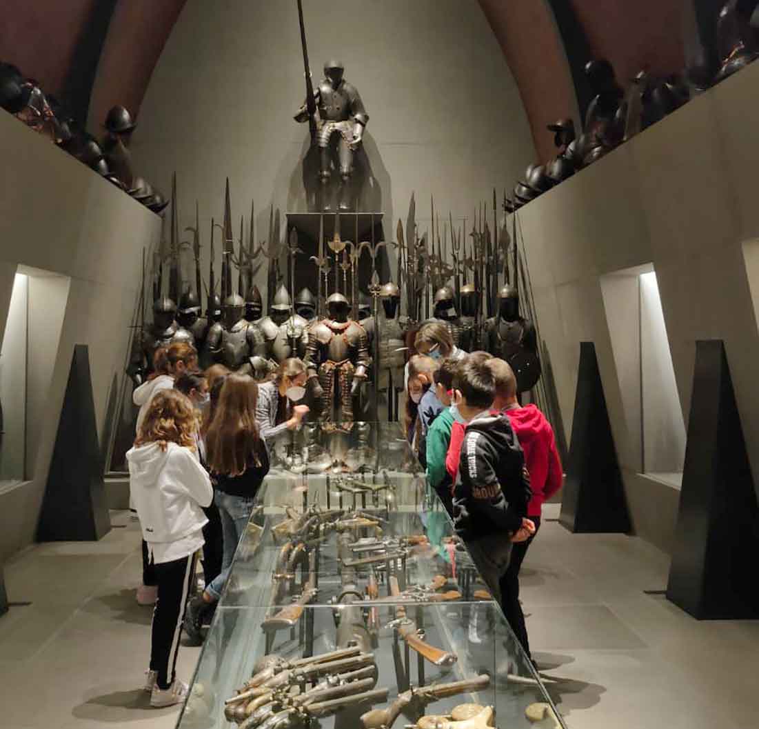 Un gruppo di bambini osserva una collezione di armature e armi medievali nella Sala d'Armi del museo Poldi Pezzoli. 