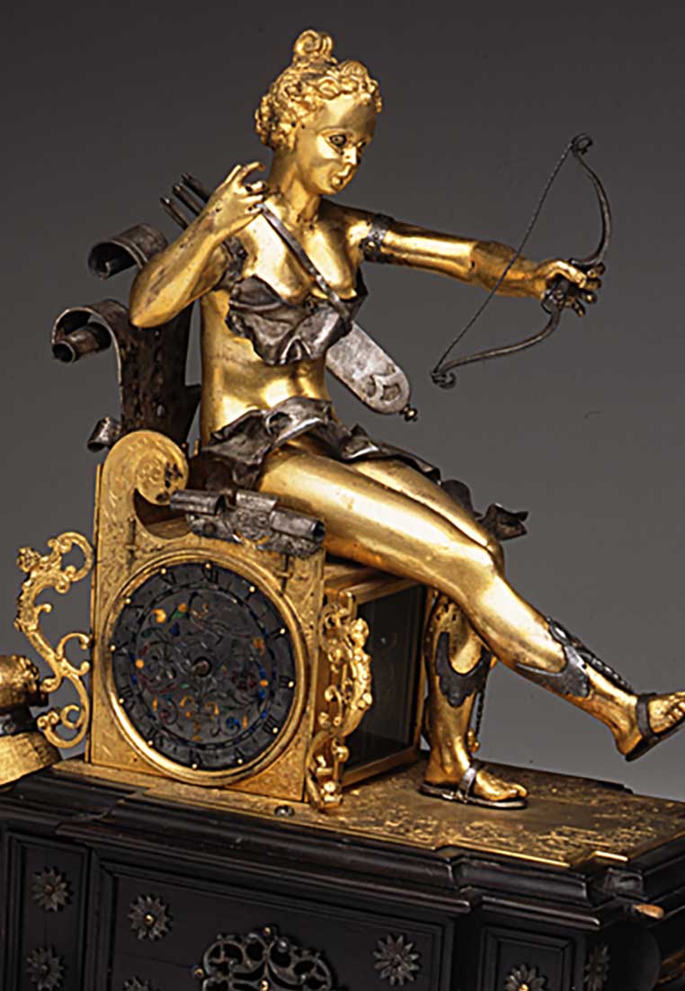Orologio a carro trionfale con automi, una giovane donna, Diana, dea della caccia, siede su un trono dorato, tende un arco, intarsi decorativi, parte di un orologio antico con dettagli intricati.