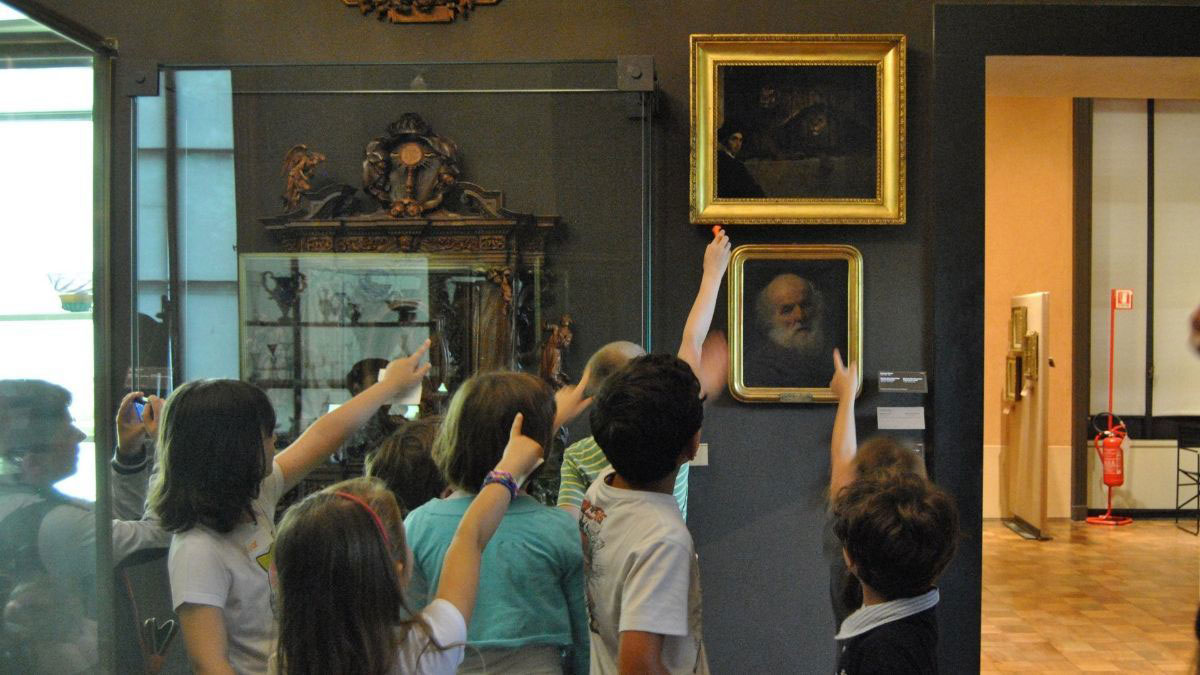 Un gruppo di bambini al museo Poldi Pezzoli guarda e indica verso un quadro di Francesco Hayez.