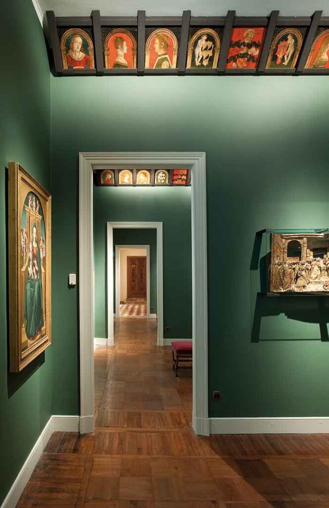La Sala dei Lombardi con pareti verdi, opere d'arte appese, pavimento in legno scuro.