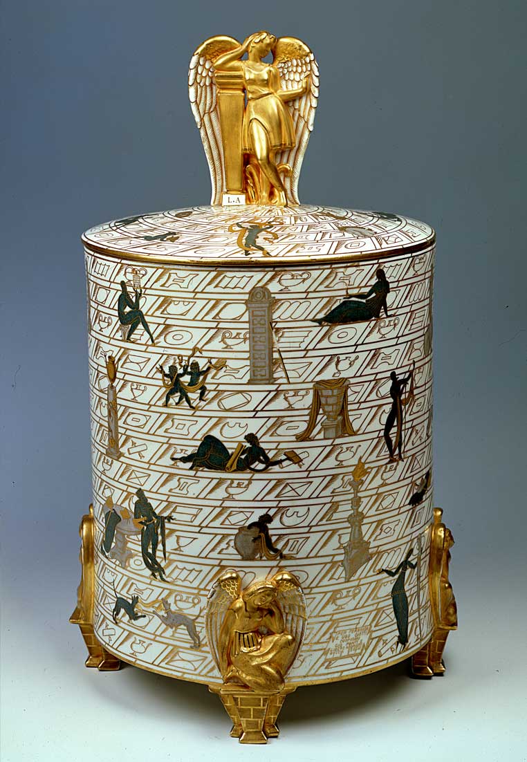 Un elegante vaso decorativo con disegni, color oro e bianco, impreziosito da figure stilizzate, ieroglifici e animale sacro sormontato da un coperchio dorato.