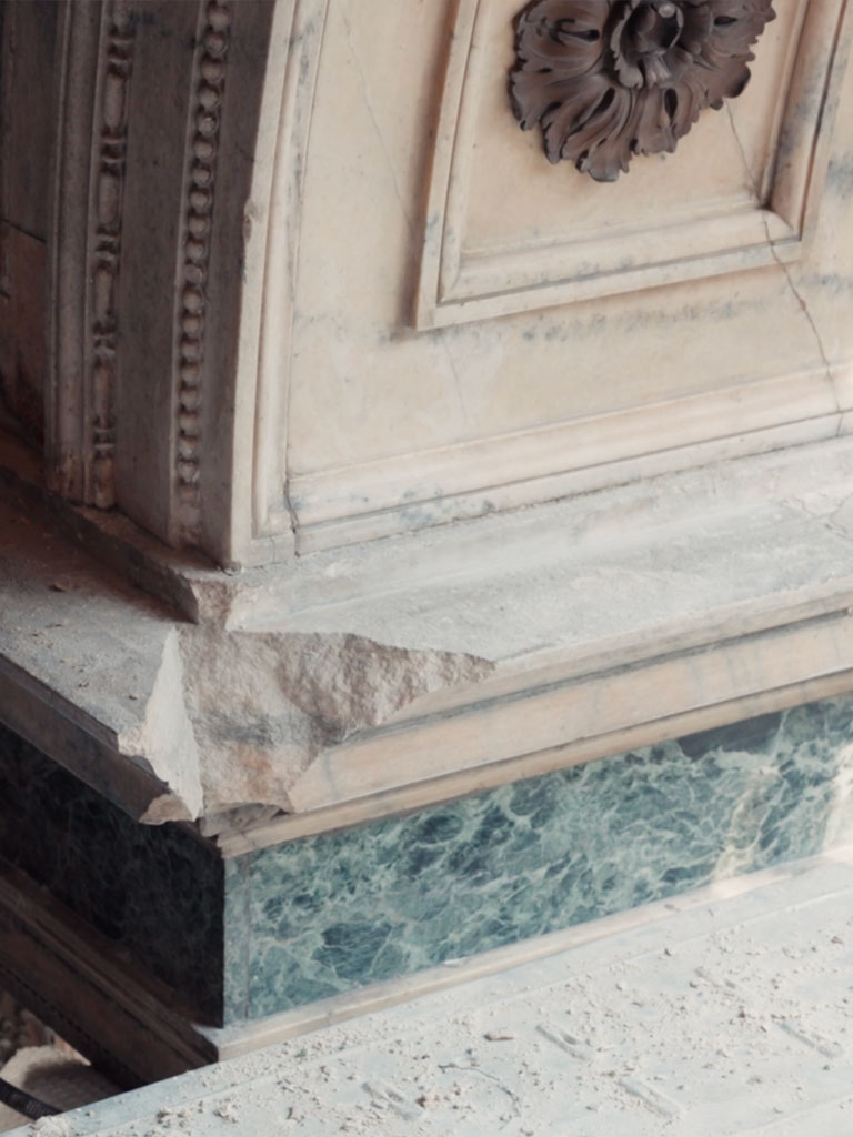 Dettaglio del basamento, con una scheggiatura nel marmo bianco e l'inserto in verde di Varallo: i segni dei cinquant'anni trascorsi sotto la copertura