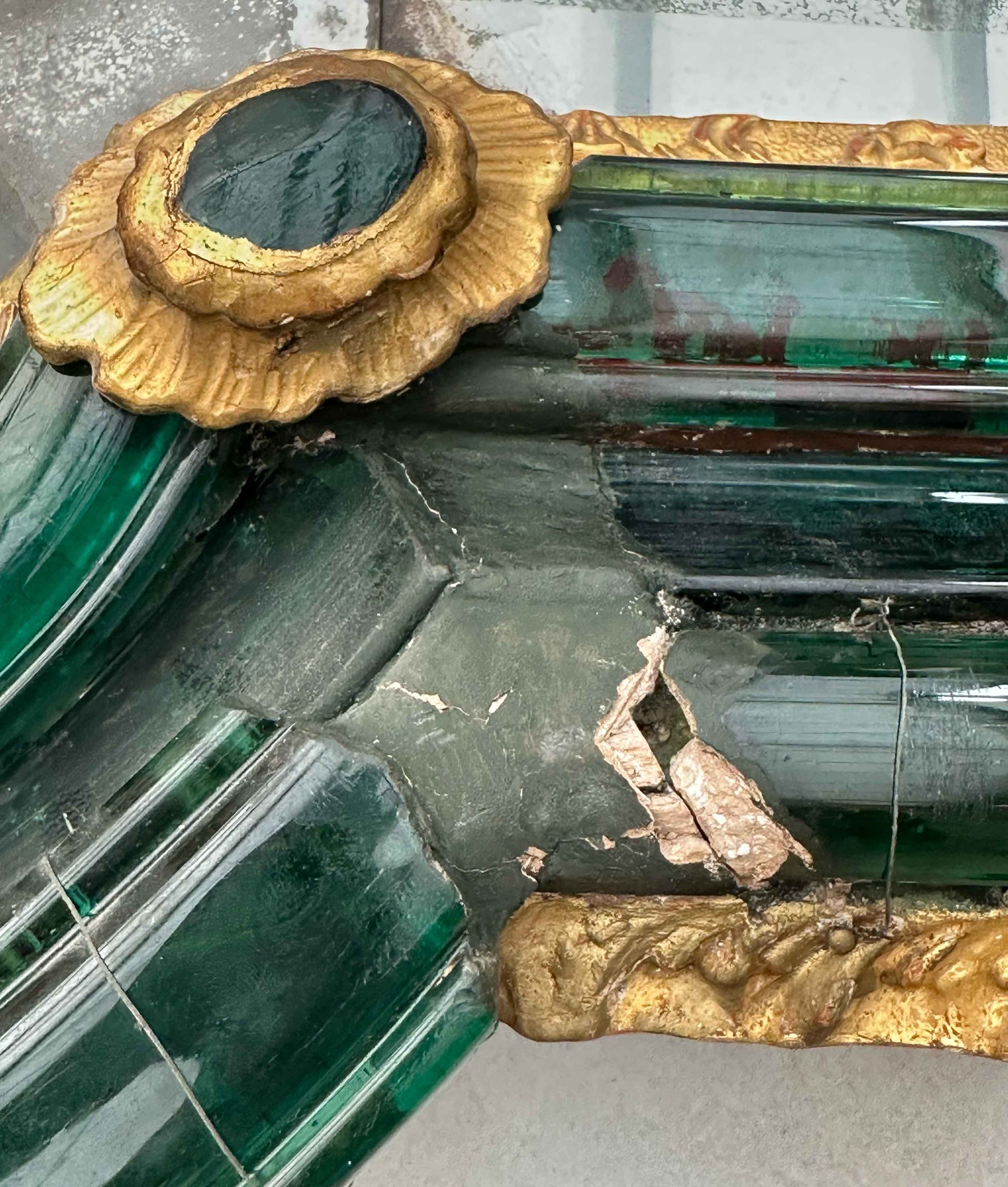 Dettaglio della cornice vitrea: le fratture e la lacuna nel vetro verde, il difetto più evidente individuato sulla specchiera